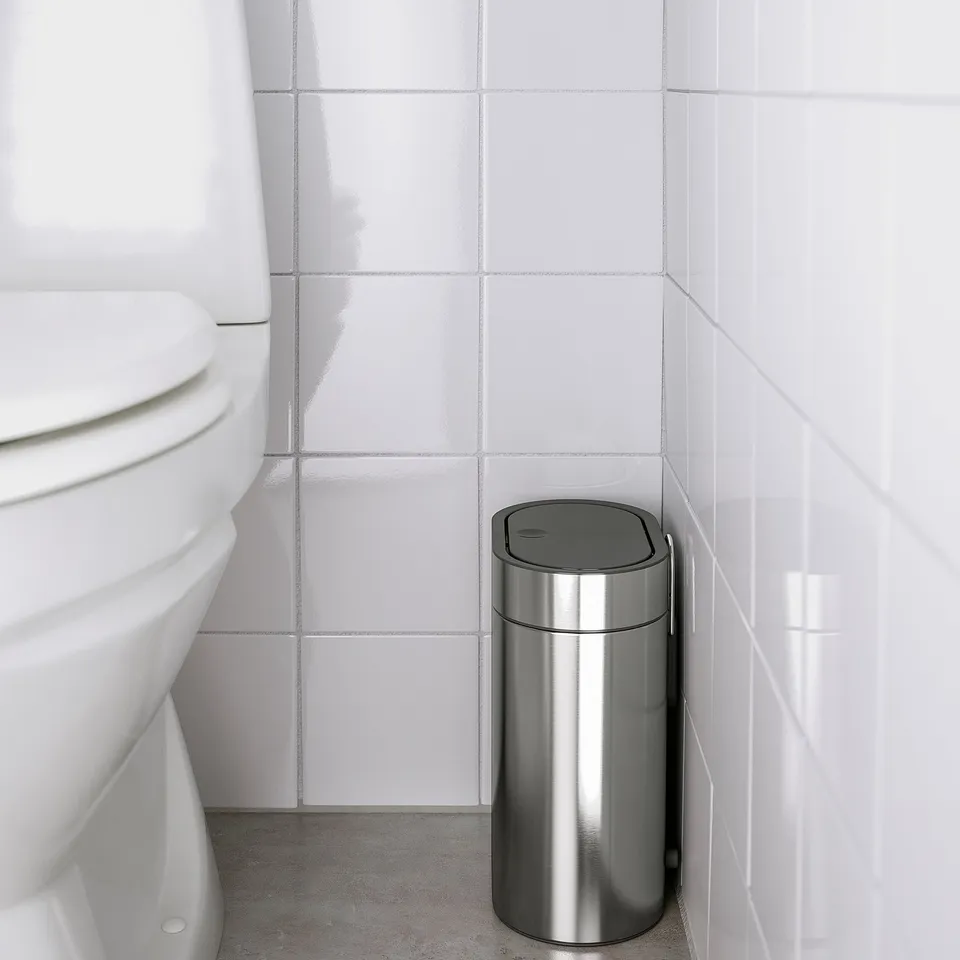 Small stainless steel bin next to a toilet, designed for narrow spaces. A fingerprint-proof surface and pedal operation.