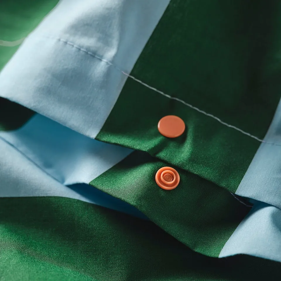Green and white striped duvet cover with orange fasteners, showing texture and durable material.