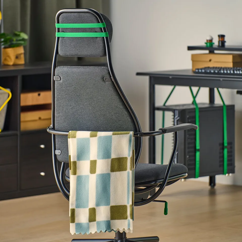 Gaming chair with adjustable headrest, seat height, and tilt function. Towel hangs on back rail.