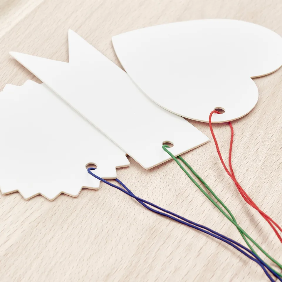 Three wooden tags: flag, heart, label, colourful strings.