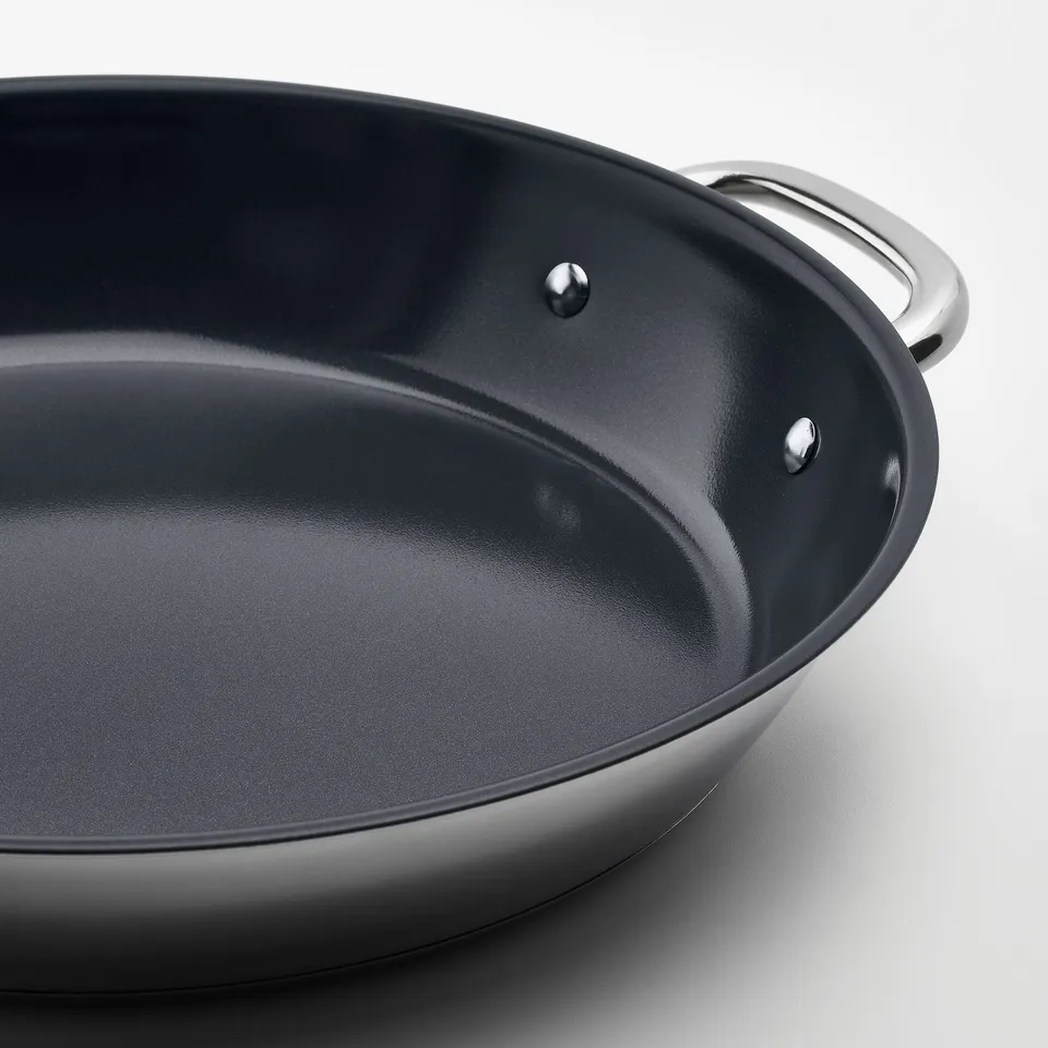 Black frying pan with stainless steel handles; smooth, non-stick surface.