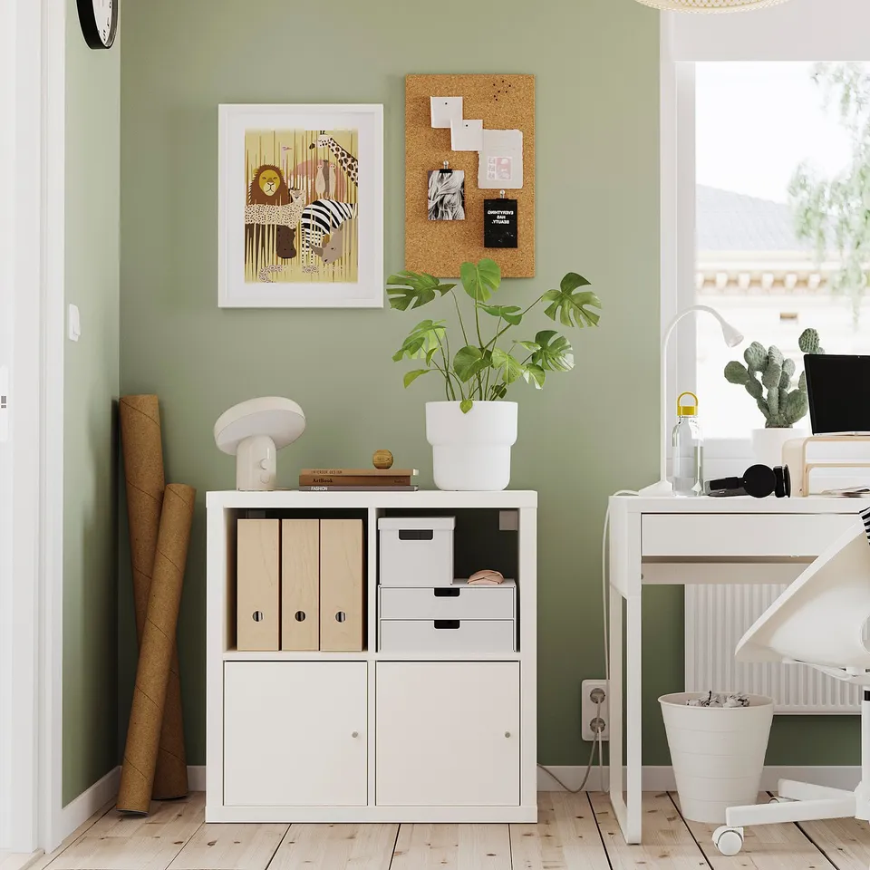 Modern office corner with KALLAX storage, plant, desk, and decor.
