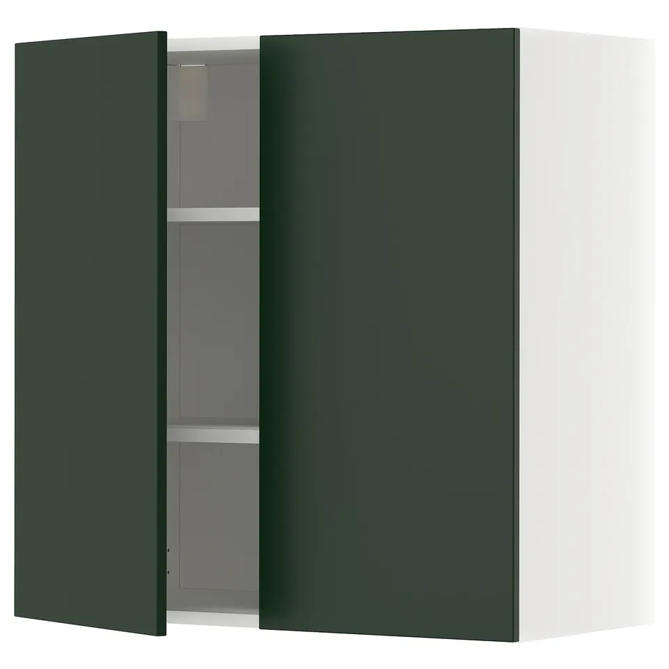 A green kitchen cabinet with one door open, revealing adjustable shelves inside.