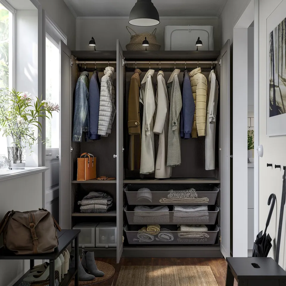 Modern closet with hanging clothes, shelves, and drawers, illuminated by a pendant lamp above.