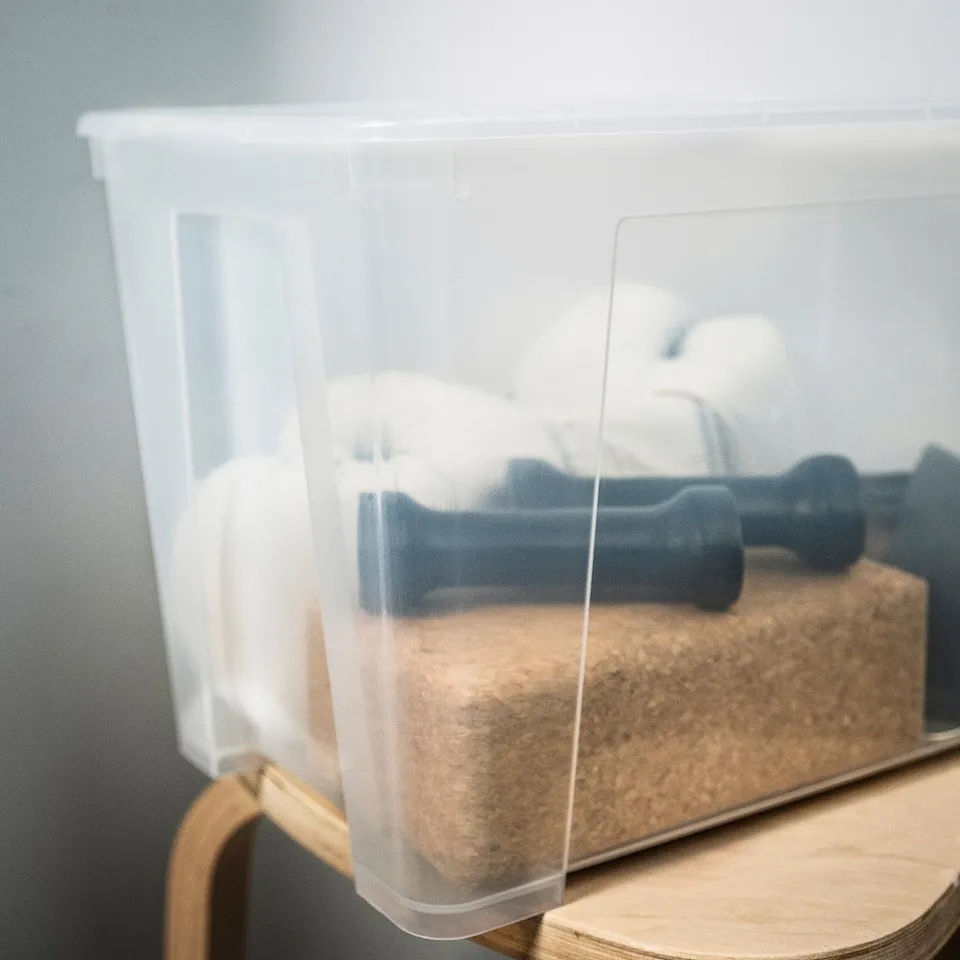 Clear plastic storage container holding sponges and blue dumbbells, showing durability and transparency.