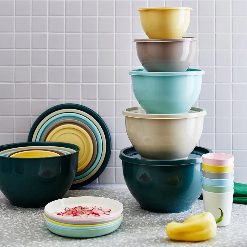 Stacked plastic bowls in various colours, nested lids, and small plates. Ideal for storing dry foods.