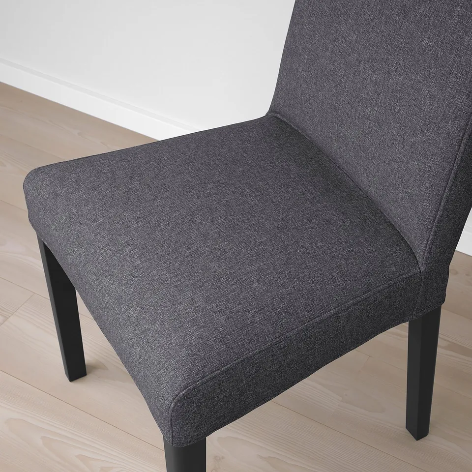 Modern black fabric chair with wooden legs on light floor. High back, clean lines, and durable materials.