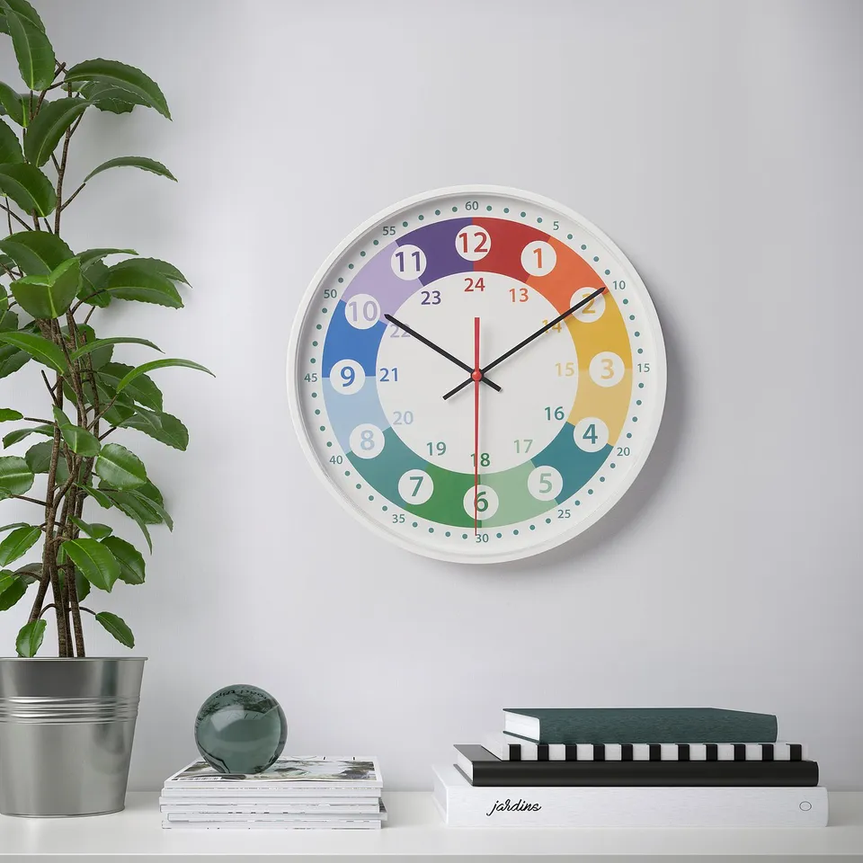 Colourful wall clock showing time zones above bookshelf with plant and sphere.
