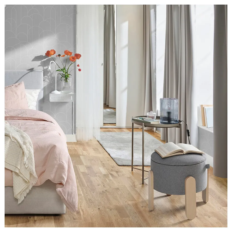 Modern bedroom with FÖRLUNDA pouffe, pink bed, book, and vase.