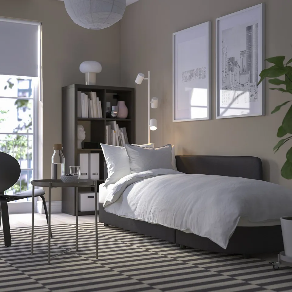 Modern bedroom with a sofa bed, side table, and plants. Sofa bed has storage, and uses round, playful shapes.