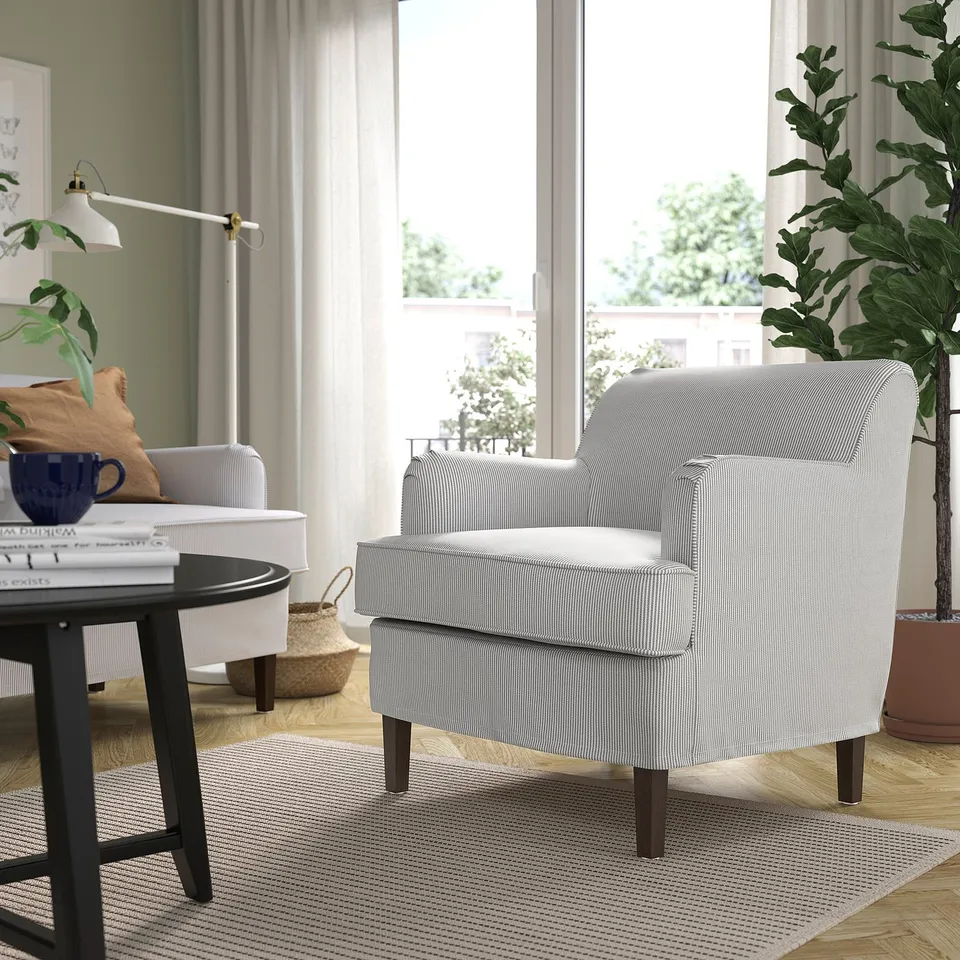 Cosy living room with armchairs, coffee table, large window, and plant.