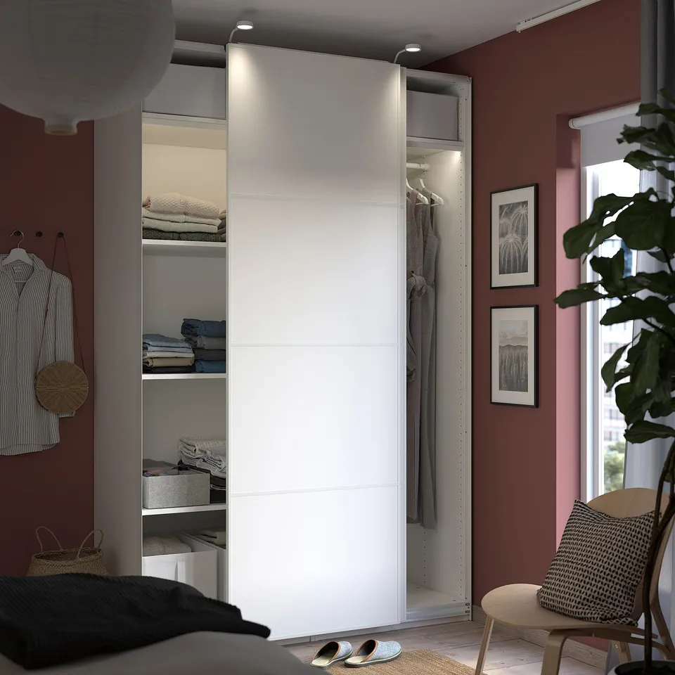 Modern bedroom with white PAX wardrobe, mirrored & solid doors, clothes & art.