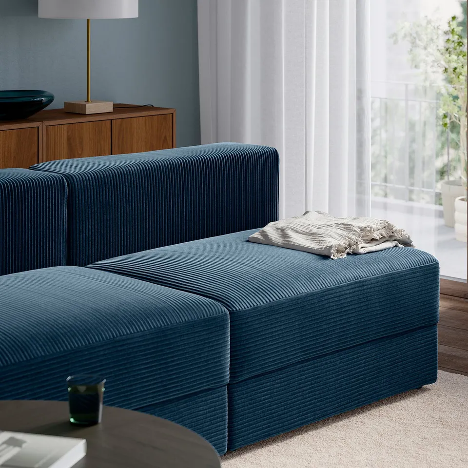 Blue modular sofa with chaise, window, & blanket.