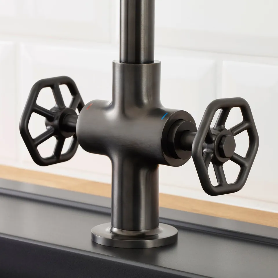 Dark industrial-style tap with large black handles and high spout.
