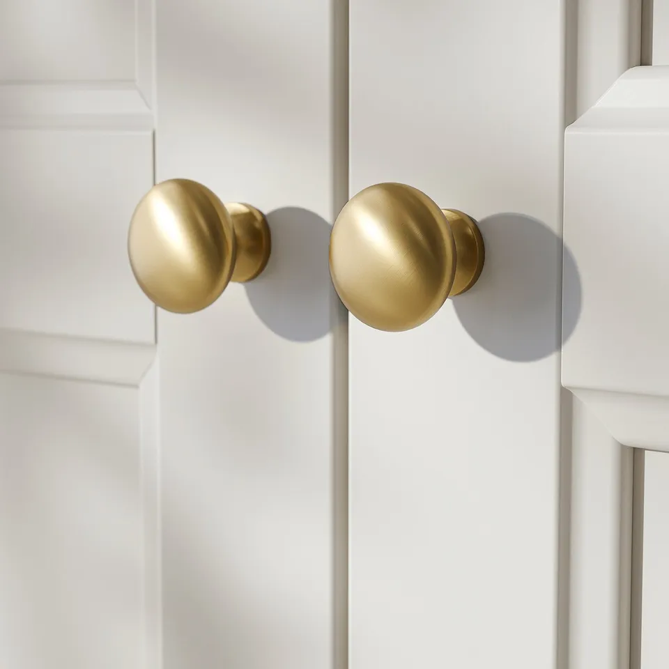 Gold knobs on white cabinet doors, showcasing sleek design and high-quality finish.