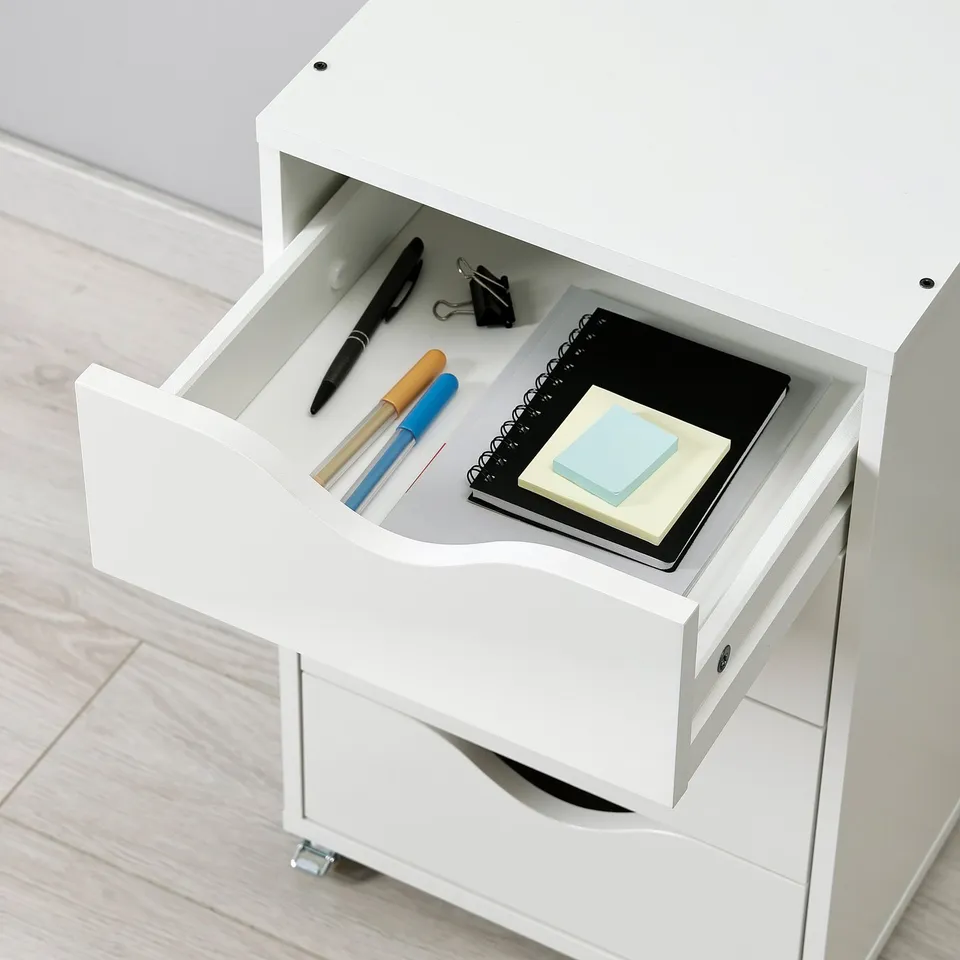 Open white drawer with office supplies: pens, notepad, sticky notes.