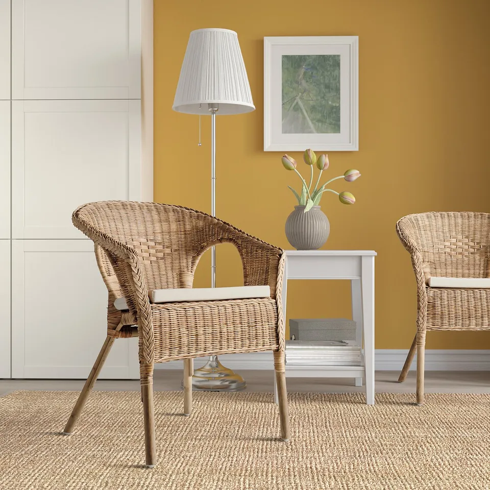 Mustard room with wicker chairs, side table, tulips, and lamp.