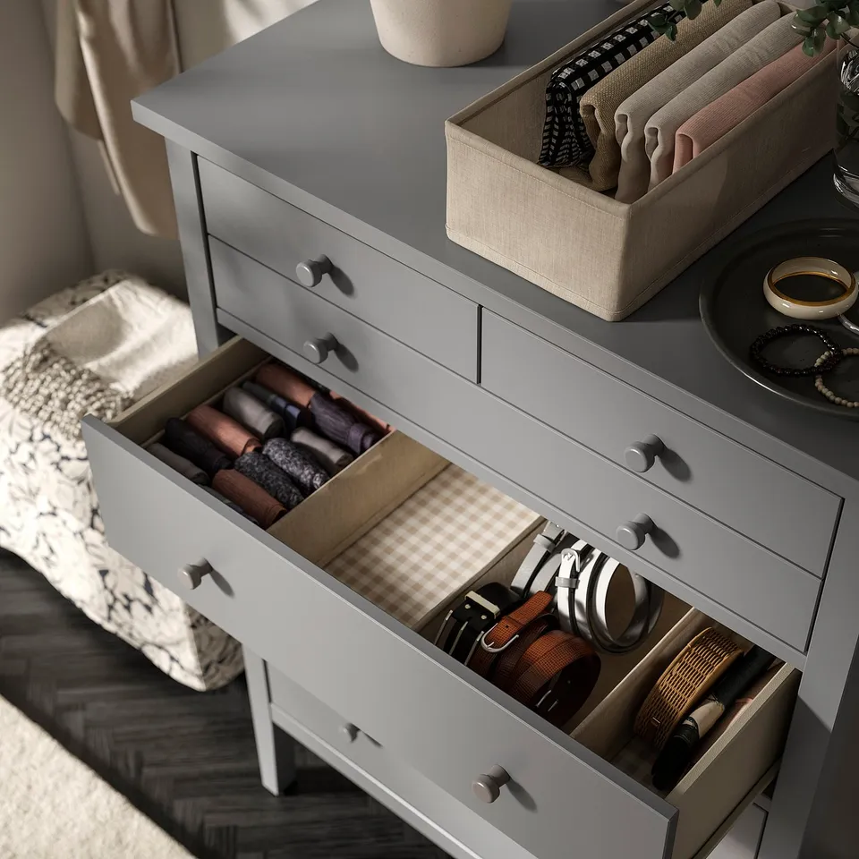 Organised dresser with open drawers, neatly storing items like belts, wallets, and headphones.