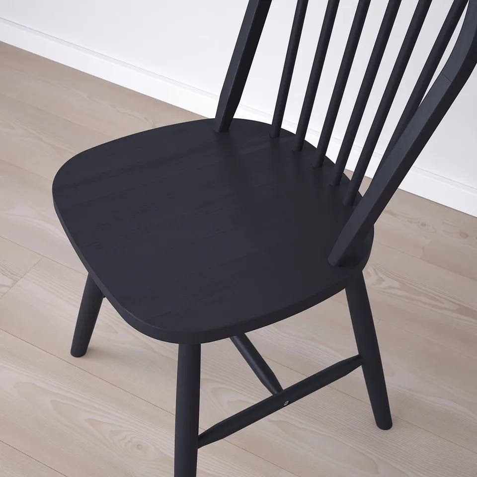 Black wooden chair on light wooden floor, shown from above. Chair a curved seat and slatted backrest, indicating high-quality craftsmanship.