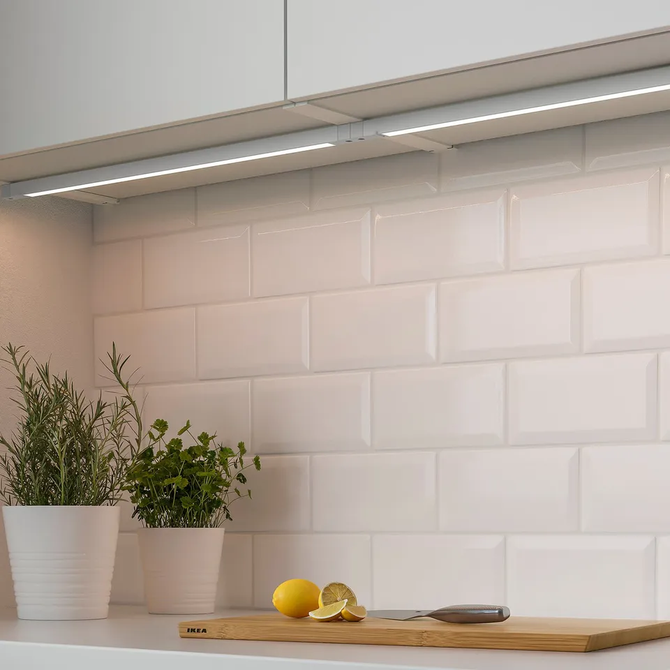 Image shows a modern kitchen counter with plants and lemons. It built-in led lighting under cabinets, offering functional and ambient light.