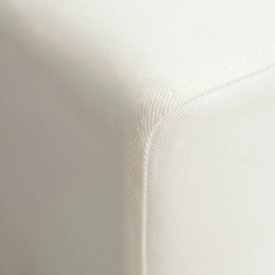 White sofas corner with detailed stitching, smooth fabric, and comfortable cushions.