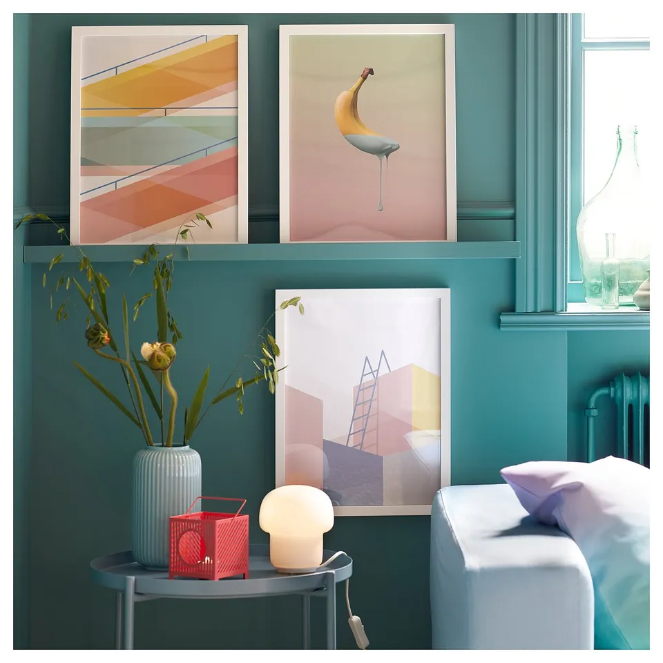 Bright room with teal walls, modern art, flower vase, red speaker, and TOKABO lamp in white glass on a small table.