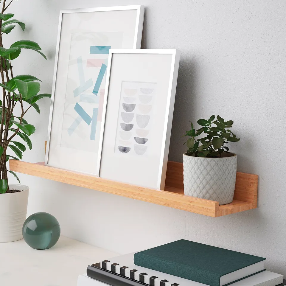 Floating shelf displays art, plants, and books. Groove holds frames at angle.