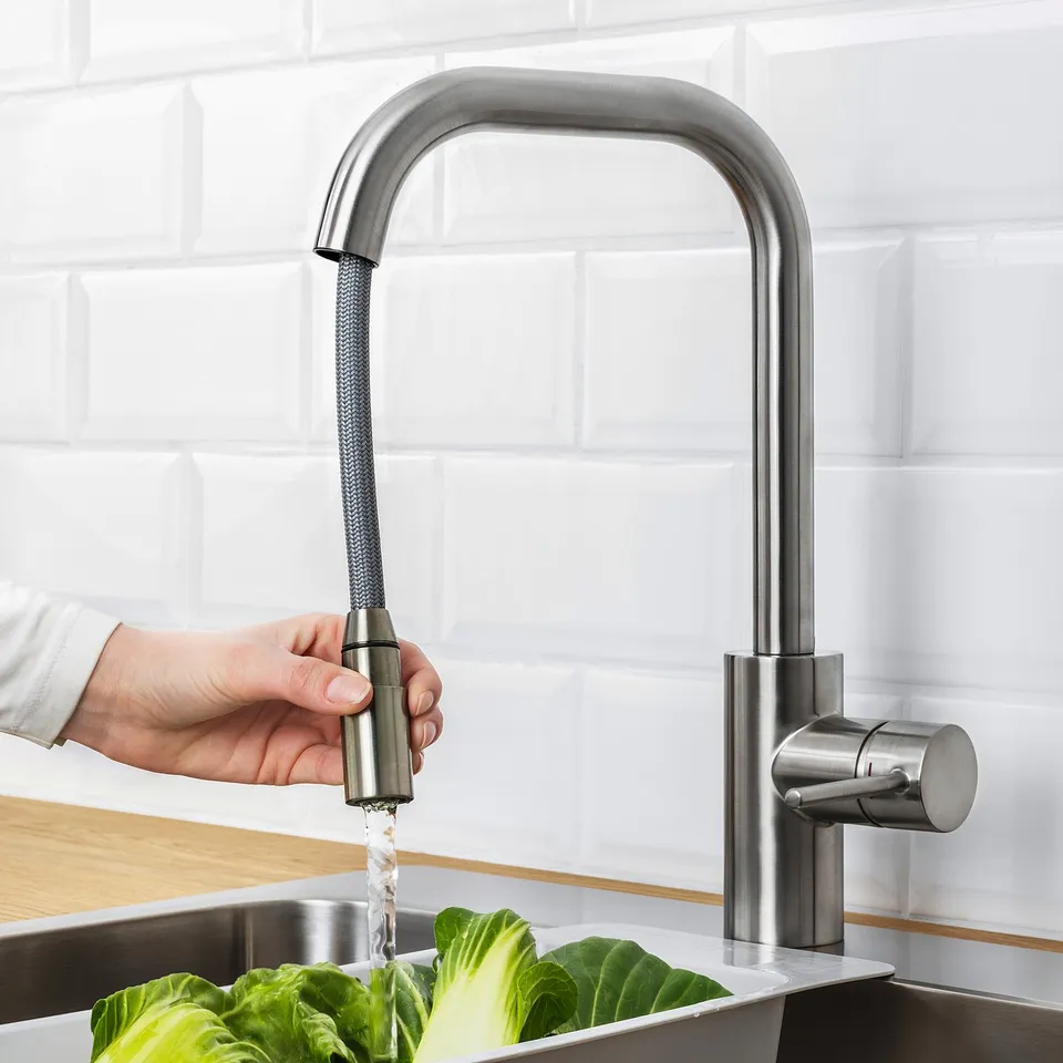 Person using ÄLMAREN taps pull-out spout to rinse lettuce in sink.