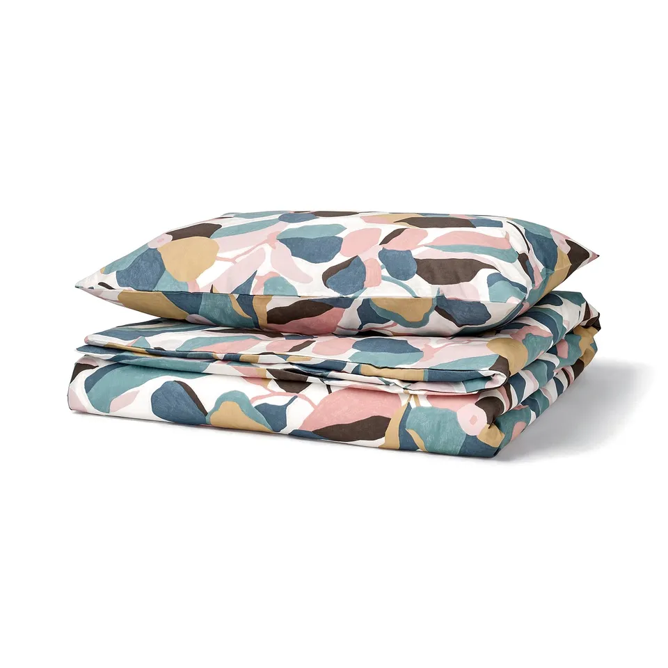 A folded VIDEOXBÄR duvet cover with an earthy leaf pattern in pink, green, and brown on a white background, made of cotton and lyocell.