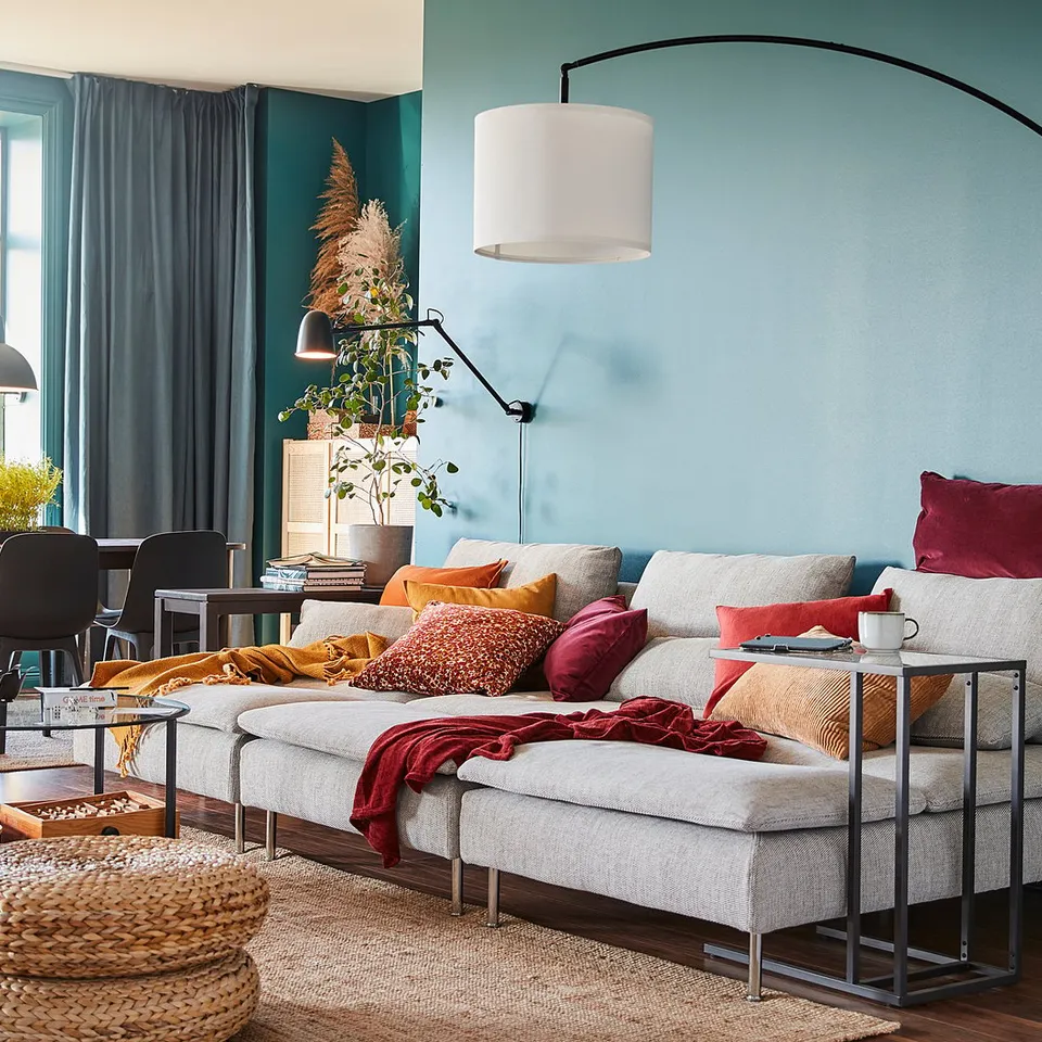 Modern living room with teal walls, SÖDERHAMN white chaise longue, colourful pillows, hanging lamp, plants, and wooden floor.