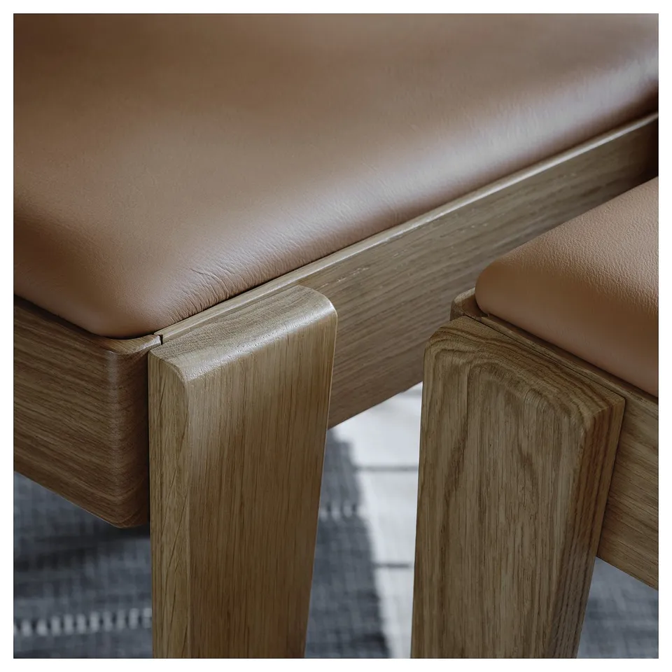 Close-up of stylish, durable dining set. Light wood meets soft leather. Quality craftsmanship evident.