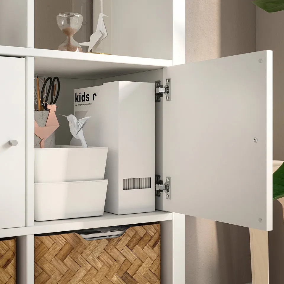 Open white KALLAX shelf unit displaying storage boxes and origami.