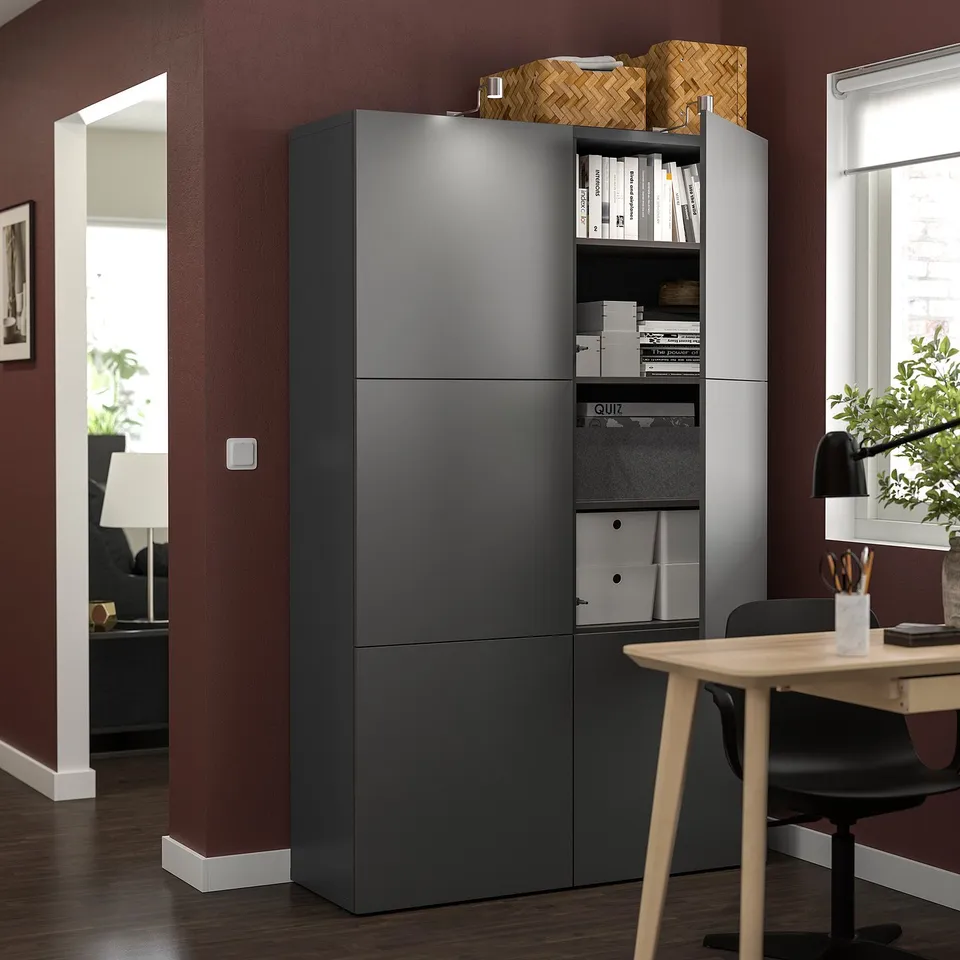 Modern office with grey BESTÅ storage unit, three sections with mixed open and closed storage. Top has baskets, middle is closed, bottom has boxes.