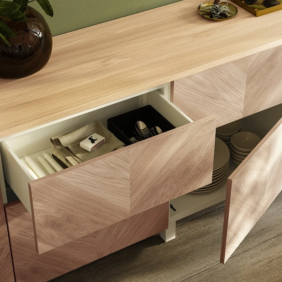 Light wood drawer unit open, showing folded napkins, cutlery tray, and plates; part of IKEA BESTÅ series.
