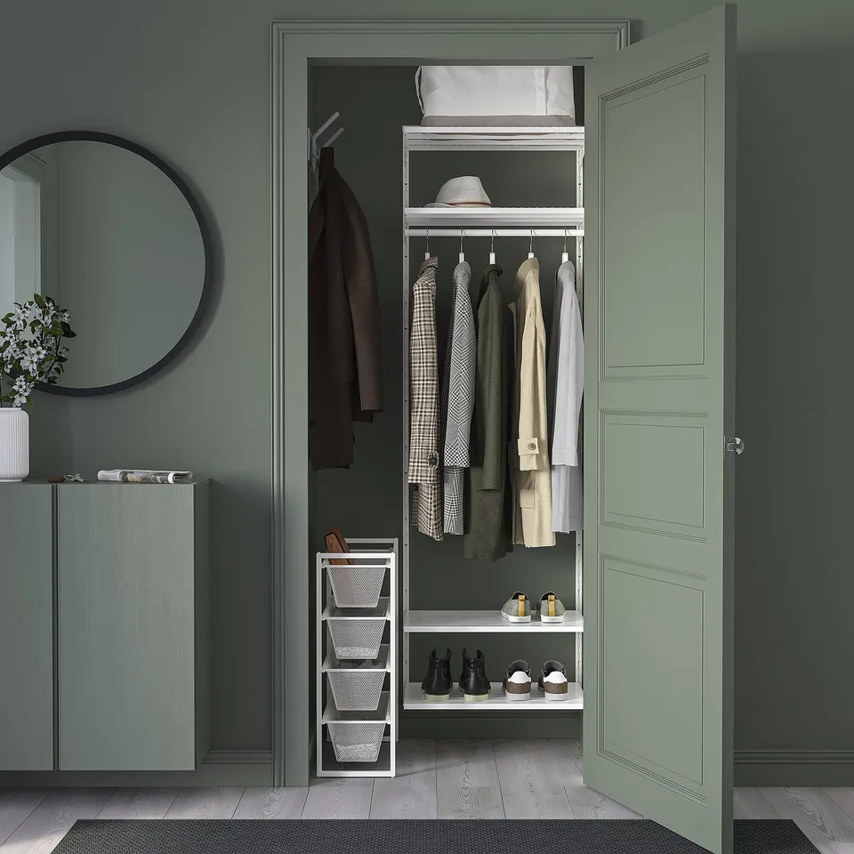 Open closet with JONAXEL storage: coats, shelves, baskets. Green walls, white shelves.