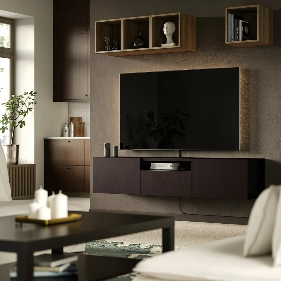 Modern living room with large flat-screen tv on BESTÅ bench, open storage, cable management, wall shelves, coffee table, plant, comfortable couch.