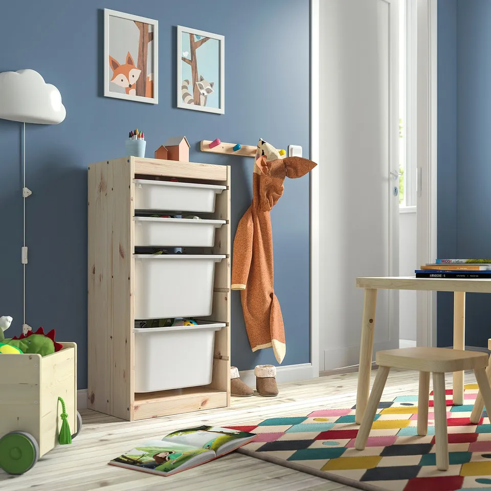 Kids playroom with blue walls, wooden furniture, colourful rug. TROFAST storage, books, toys, giraffe plush.