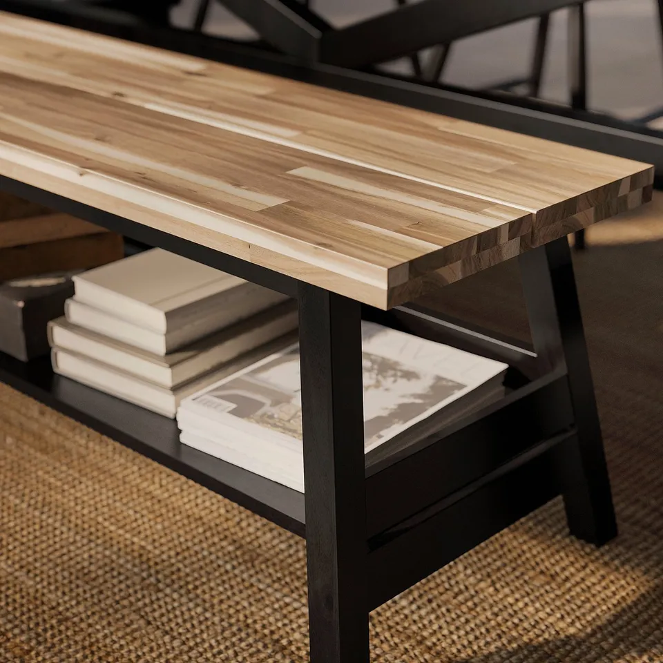 Wooden bench with metal legs, showcasing lower shelf holding books, offering storage.