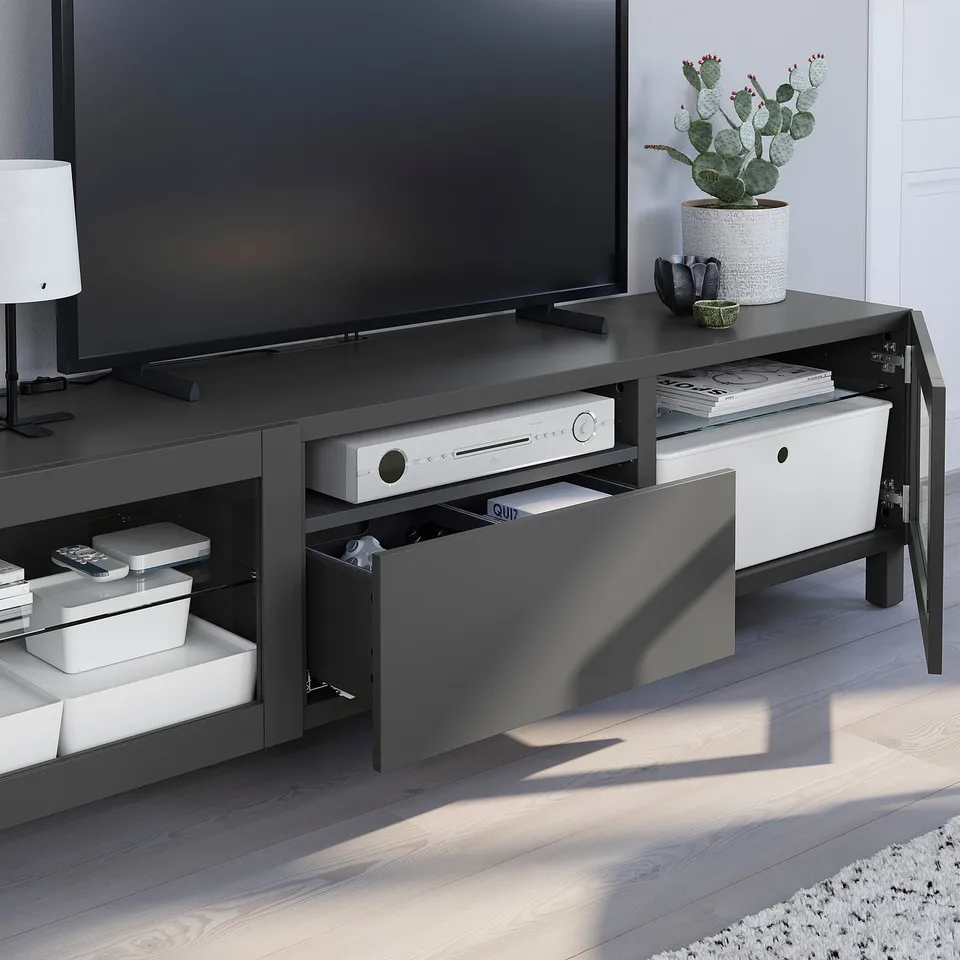 Modern tv stand with multiple storage drawers, holding electronics and decor.