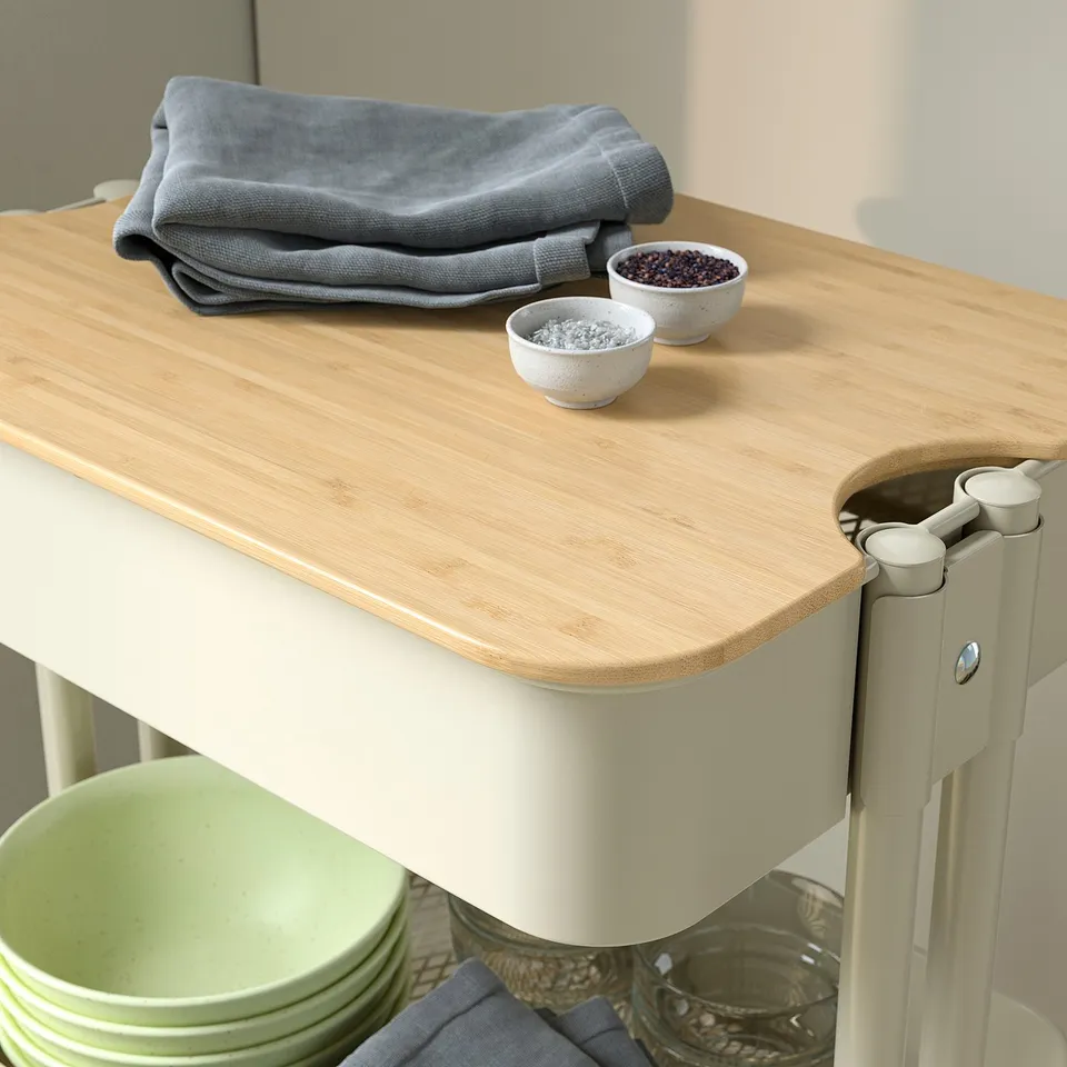 Small kitchen trolley with wooden top, holding grey cloth, and two bowls of spices; built-in shelves with dishes and jars below.