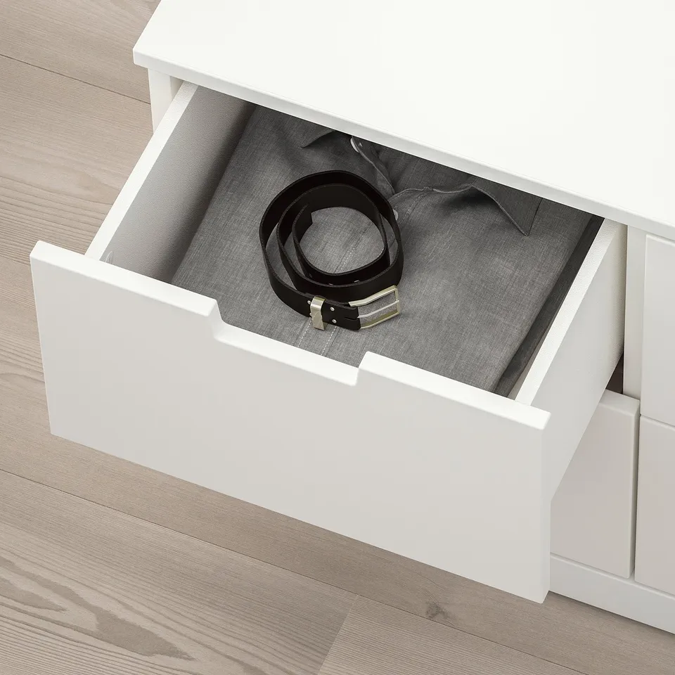White NORDLI drawer open, revealing belt and shirt inside, showcasing storage space.