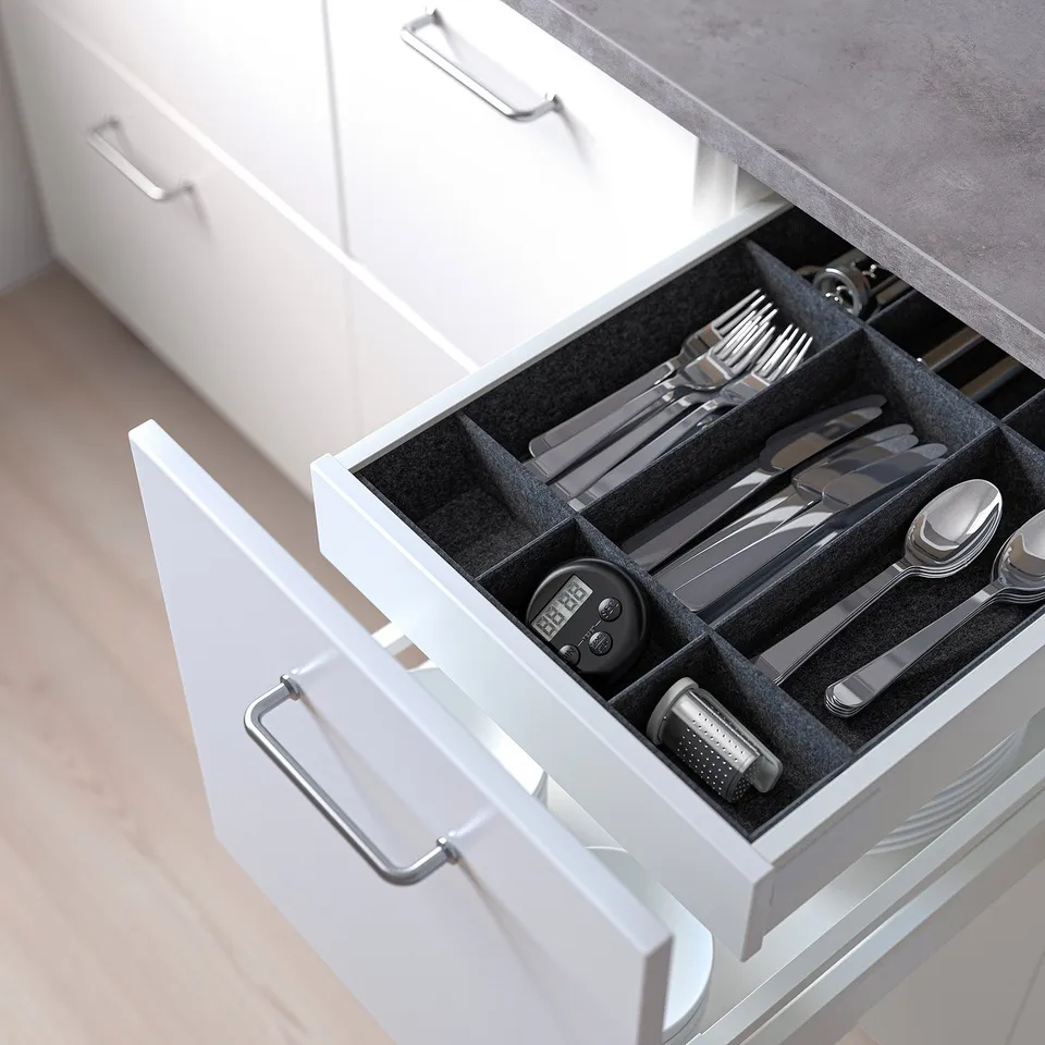 Open kitchen drawer revealing organised cutlery and kitchen tools in white drawer with dividers