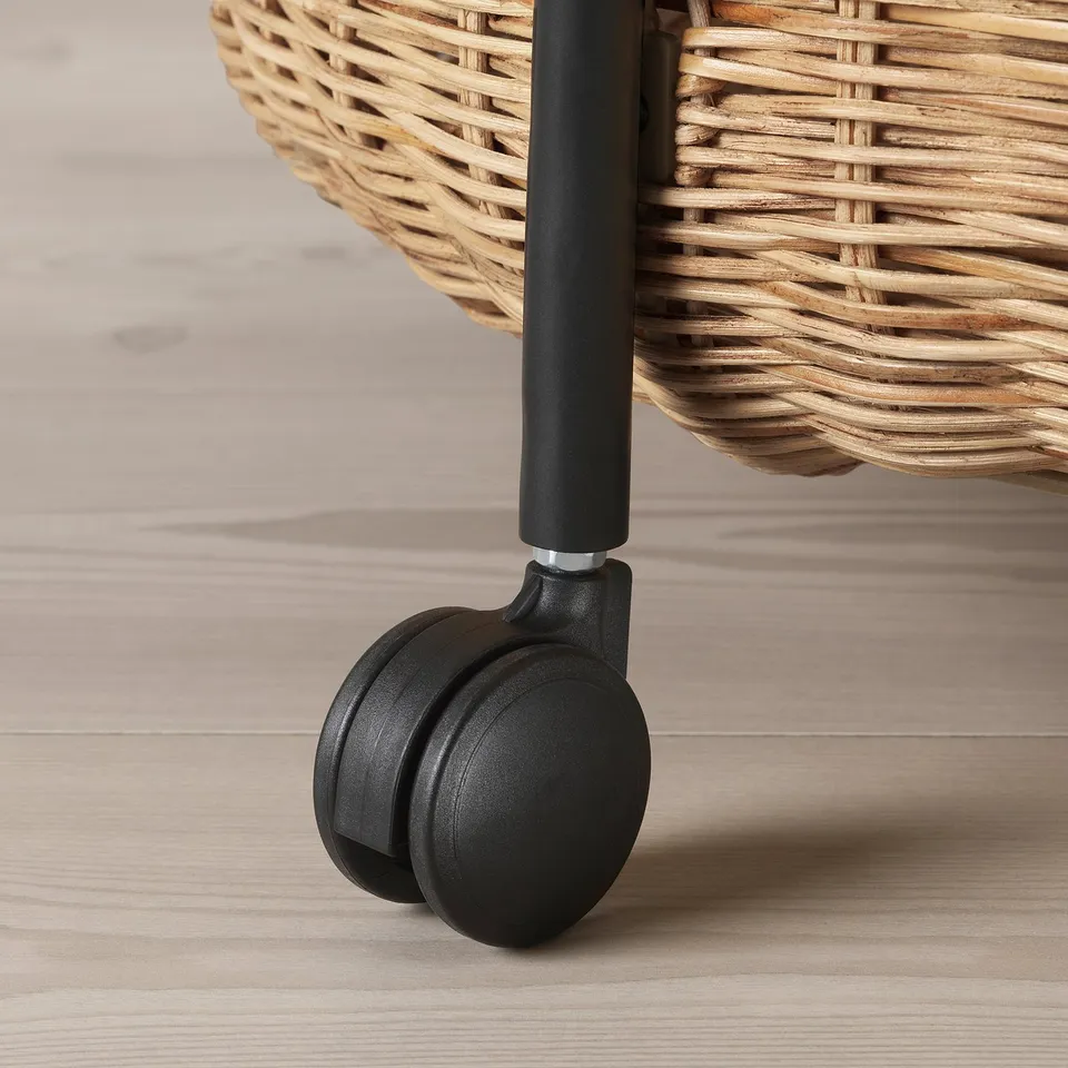 Close-up of wicker basket trolley with sturdy black wheel.