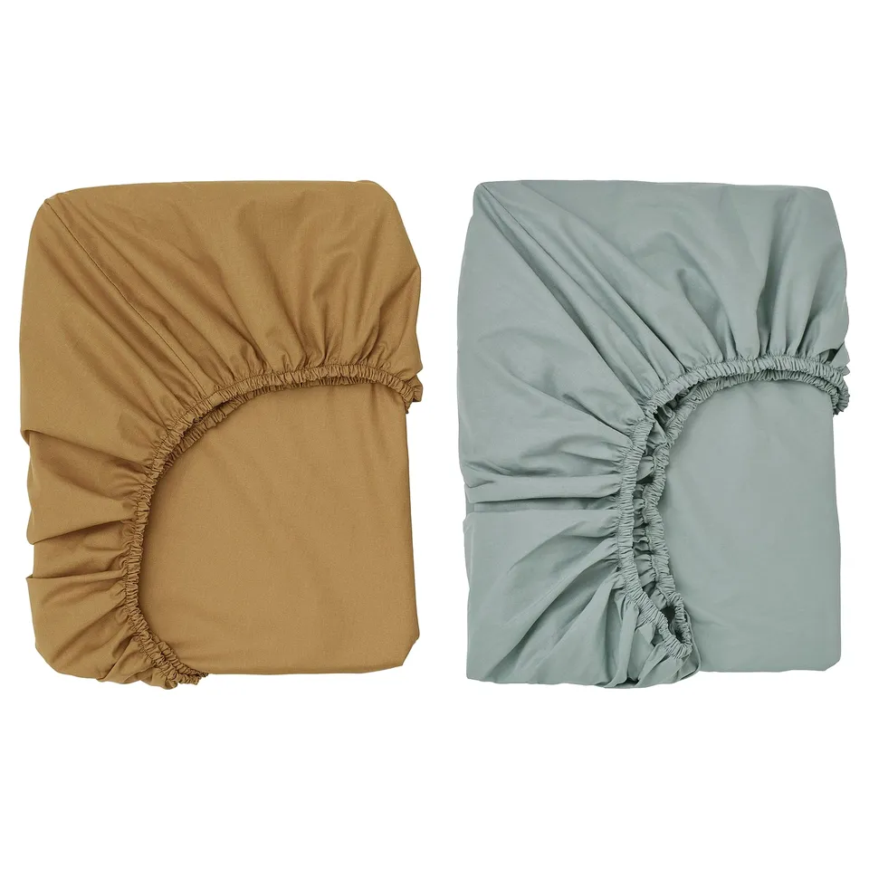 Two folded fitted sheets: one tan, one light blue. Both rectangular, elastic edges, organic cotton, GULDVÄVARE brand.