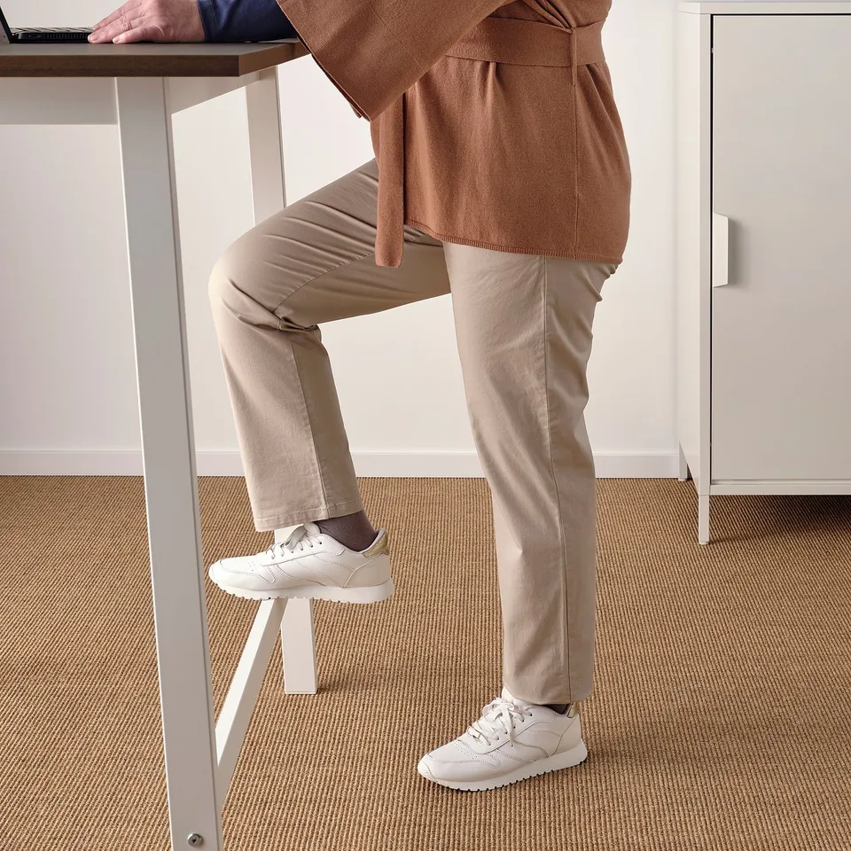 Person using footrest while working at a high table, promoting active sitting or standing.