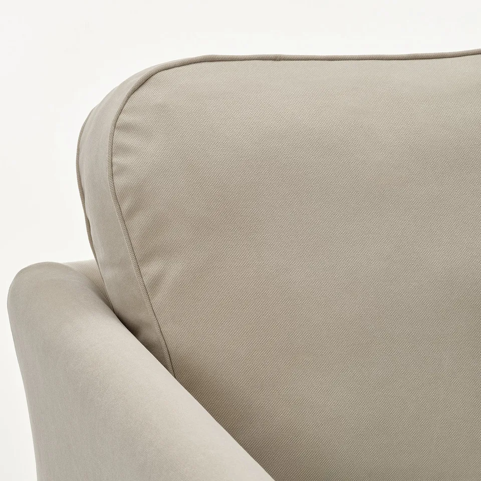 Beige upholstered sofa corner with soft, smooth fabric and supportive cushions.