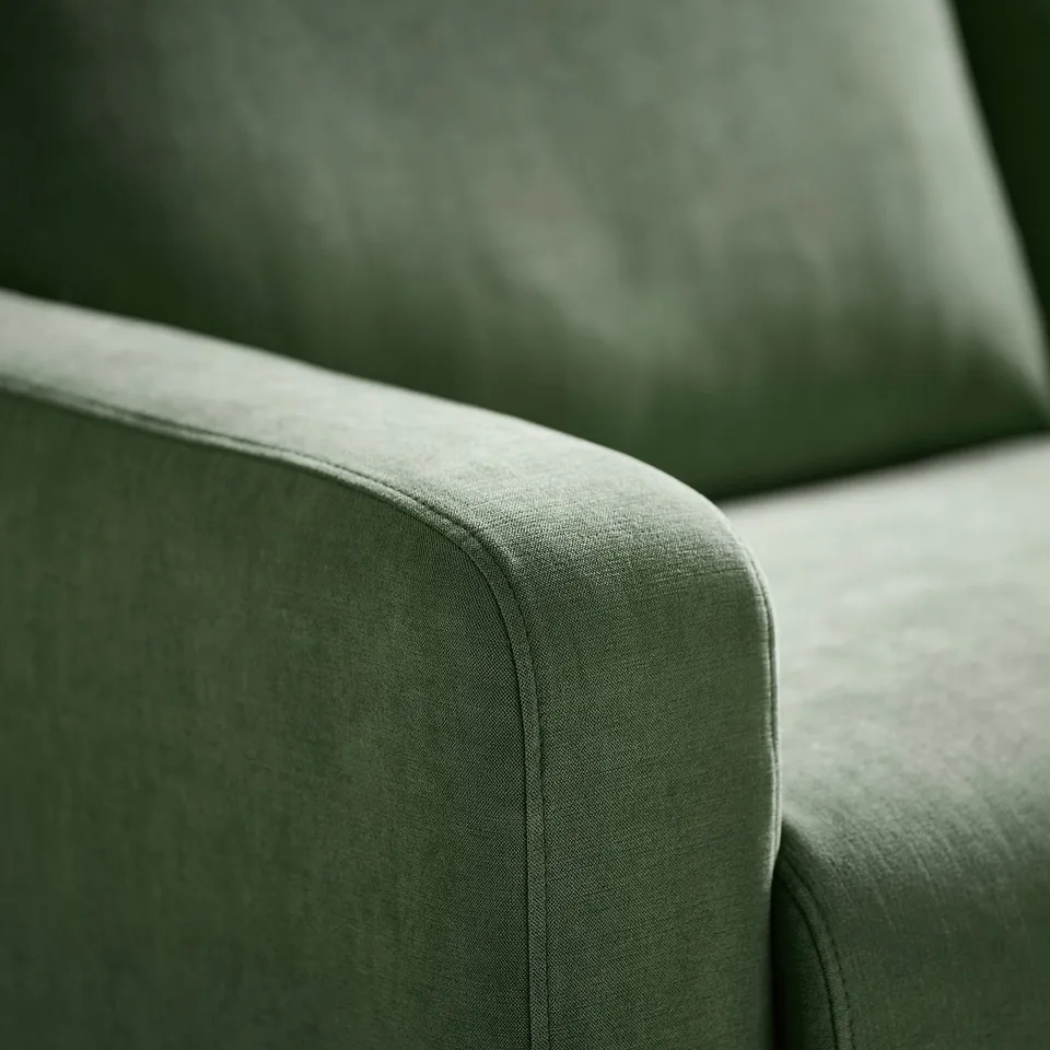 Close-up of a plush, green sofas armrest, showcasing its soft, textured chenille fabric and sturdy design.