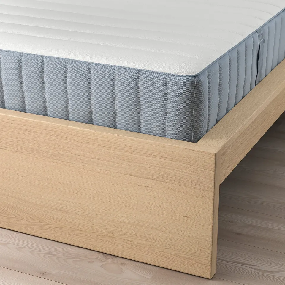 A wooden bed frame with adjustable sides supporting a white mattress. The slatted base ensures comfort and mattress suppleness.
