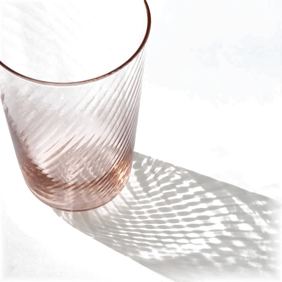 Elegant, thin glassware with a smooth exterior and rippled interior casts a sophisticated shadow.