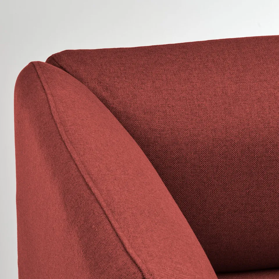 Close-up of a modern, deep-red sofa corner. High-quality fabric, neat stitching, durable design.